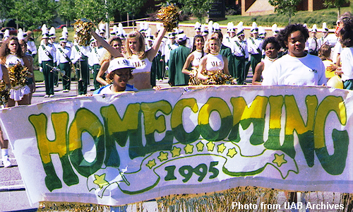 Cheerleaders carry a homecoming banner in front of the band
