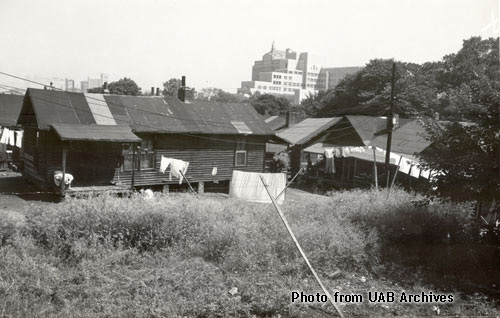 Rundown shack in a field with high rise buildings behind it