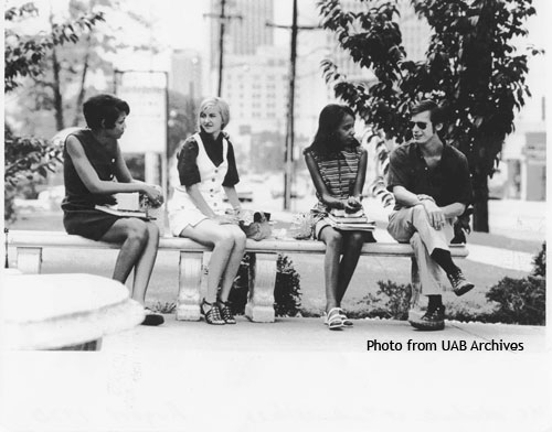 Three women and a man sit on a bench talking
