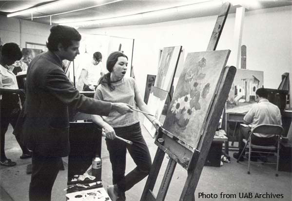 A professor points to a painting while a student looks on