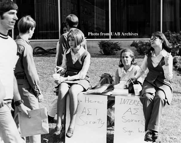 Women sent and behind a table recruiting for a sorority