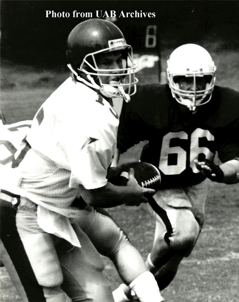 A UAB quarterback runs with the ball with a opponent to his side