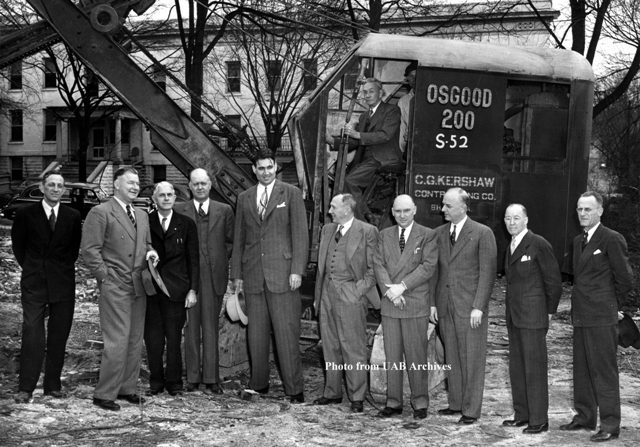 A group of men stand on the construction site for the Medical Center