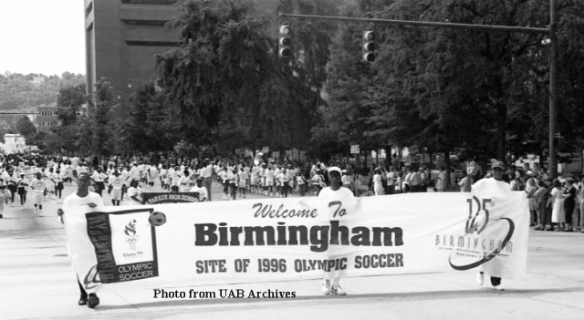 Three men march with a banner in front of a parade