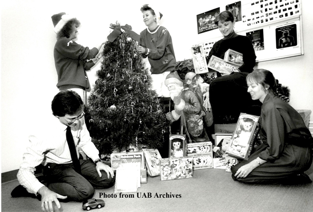 Several staff members decorate a Christmas tree and play with donated toys